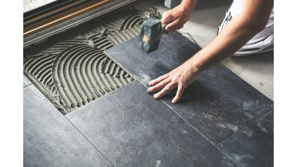 a person using a hammer to lay a tile on the floor